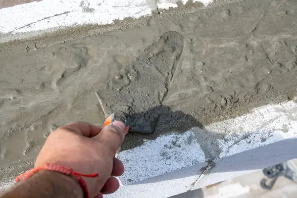 Somut çözelti dökülüyor. El çözeltiyi yumuşatmak için bir spatula tutuyor. Kendi ellerinle bir ev inşa etmek. Yüksek kalite fotoğraf