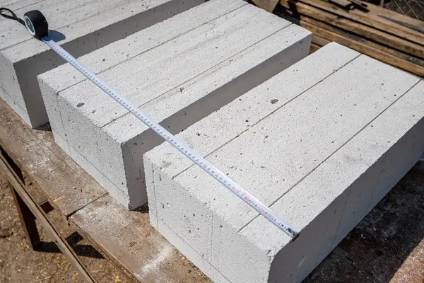 stock image White aerated concrete blocks close-up. Measuring the size of a gas block with a tape measure. Construction of a house from aerated concrete blocks and bricks. High quality photo