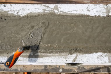 Spatula çözeltiyi yumuşatmak için. Somut çözelti dökülüyor. Kendi ellerinle bir ev inşa etmek. Yüksek kalite fotoğraf