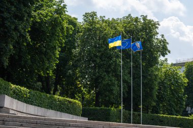 Ukrayna bayrak direğinde, Avrupa Birliği 'nin bayrağı ile aynı anda, arka planda yeşil ağaçlar. Yüksek kalite fotoğraf