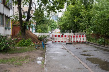 Bir yerleşim bölgesinin avlusunda kazılmış bir siperin etrafında çit çekmek. Kanalizasyon tamiri, boru hattı. Yüksek kalite fotoğraf