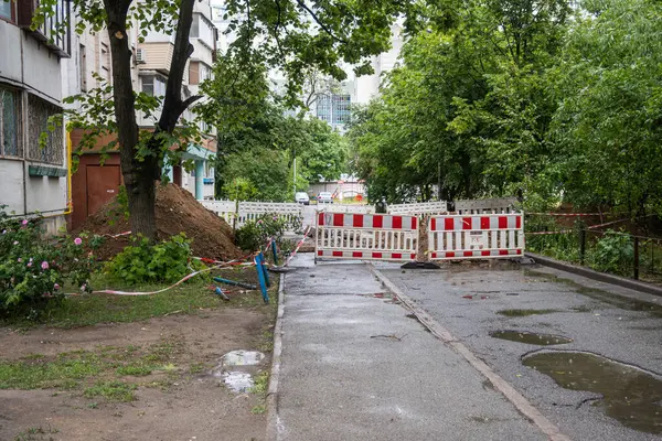 Bir yerleşim bölgesinin avlusunda kazılmış bir siperin etrafında çit çekmek. Kanalizasyon tamiri, boru hattı. Yüksek kalite fotoğraf
