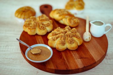 Tahta bir masada tereyağlı, sütlü ve tarçınlı taze çörekler.