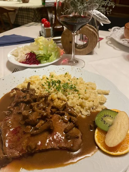 beef steak covered with gravy and chanterelle mushrooms served with spaetzle a tradional bavarian and austria pasta