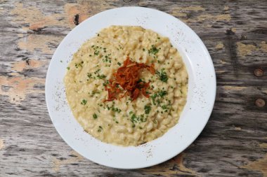 Geleneksel erişte ve peynirli beyaz tabak eski ahşap bir yüzeyde sunuluyor.