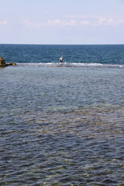 Balıkçı oltasını atmak için sığ sularda duruyor.