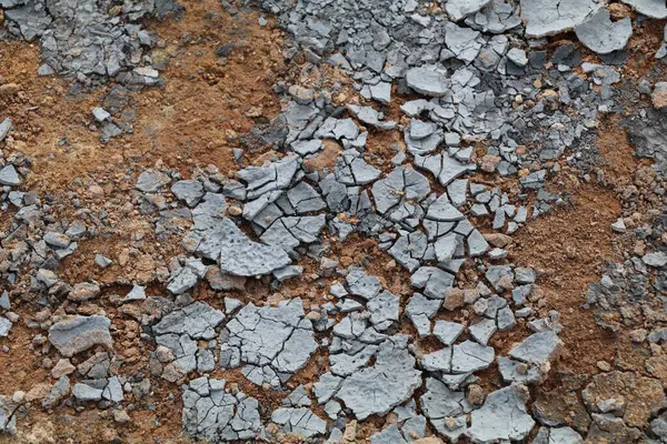 Kırmızı toprağın üstündeki gri toprağın kuru ve çatlak kabuğunun ayrıntıları.