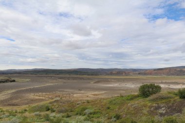 İzlanda 'nın dağlık bölgelerinde volkanik bir manzara. Siyah kum, renkli dağlar ve kaygı verici bulutlarla kaplı bulutlu bir gökyüzü.