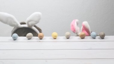  Babası ve kafalarında tavşan kulakları olan oğlu Paskalya süslemeleriyle dolu tahta bir masanın altına saklanıyorlar. Paskalya tatili