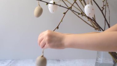 Çocuklar Paskalya dekoratif yumurtalarını bir dala asar. Yüksek kalite 4k görüntü