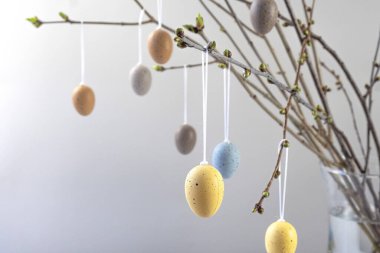 Gray background with colorful Easter eggs hanging on cherry blossom branches. High quality photo