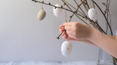 Çocuklar Paskalya dekoratif yumurtalarını bir dala asar. Yüksek kalite 4k görüntü