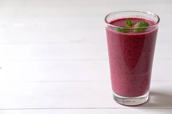 Beyaz arka planda cam içinde lezzetli yaban mersini smoothie. Yüksek kalite fotoğraf