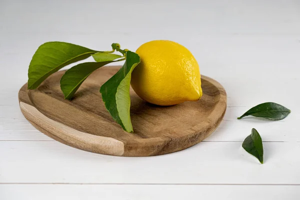 Lemon with leaves on wooden plate white background. High quality photo