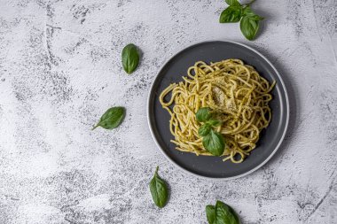 Pesto soslu makarna ve gri kasede taze fesleğen yaprağı. Açık gri arkaplan. Üst Manzara. Yüksek kalite fotoğraf
