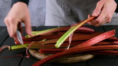 Kadınların elleri raventin saplarını temizler. Rhubarb 'ı pişirmeye hazırlıyorum. Rubarb turtası..