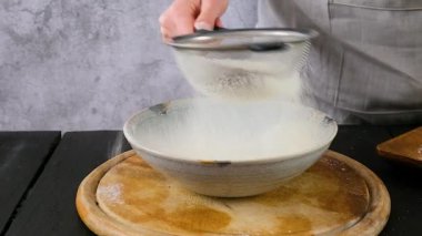 Kadın yakın çekim görüntüsü için süzgeçten un geçiriyor. Evde mutfakta kek pişirmek için un hazırlıyorum. - Evet. Yüksek kaliteli FullHD görüntüler