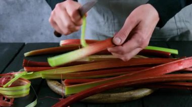Kadınların elleri raventin saplarını temizler. Rhubarb 'ı pişirmeye hazırlıyorum. Rubarb turtası..