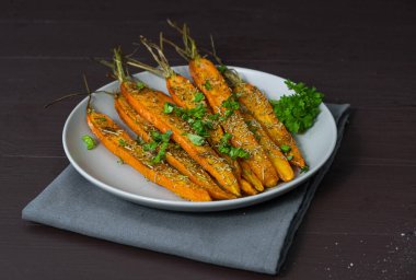 Kahverengi arka planda bir tabakta pişmiş havuç. Yüksek kalite fotoğraf