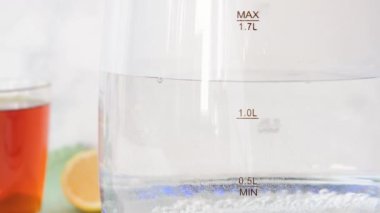 Sıcak suda cam çaydanlığın içinde kaynayan bulanık kabarcıklar. Mutfaktaki şeffaf su ısıtıcısına yakın çekim. Yüksek kalite 