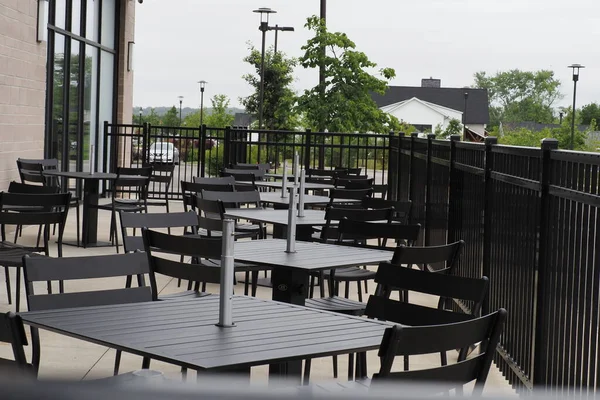 Restoranın açık havası verandada siyah metal masalar ve sandalyelerle dolu..