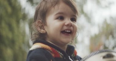 Dışarıda tef çalan tatlı bir kız bebek. 4K RAW 'da bir sinema kamerasında çekildi..