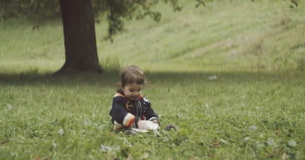 かわいい赤ちゃんの女の子がタンバリンを屋外で遊んでいます シネマカメラで4K Rawで撮影 — ストック動画