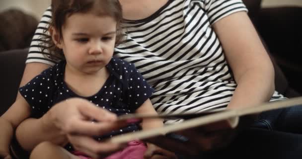 幼い娘と本を読んでいる若い母親 シネマカメラで4K Rawで撮影 — ストック動画