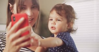 Smartphone 'da videolu sohbet eden mutlu anne ve bebek kız. 4K RAW 'da bir sinema kamerasında çekildi..
