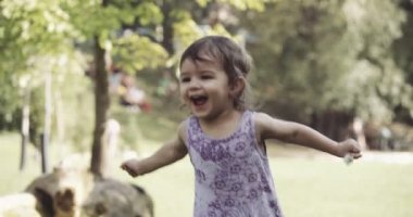 Yaz sonlarında parkı gezen ve neşe içinde zıplayan tatlı bir kız. 4K RAW 'da bir sinema kamerasında çekildi..
