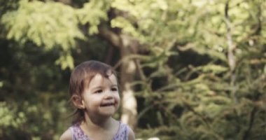 Yaz sonlarında parkı gezen ve neşe içinde zıplayan tatlı bir kız. 4K RAW 'da bir sinema kamerasında çekildi..