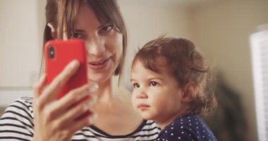 Smartphone 'da videolu sohbet eden mutlu anne ve bebek kız. 4K RAW 'da bir sinema kamerasında çekildi..