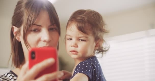 スマートフォンでビデオチャットをしている幸せな母親と赤ちゃんの女の子 シネマカメラで4K Rawで撮影 — ストック動画