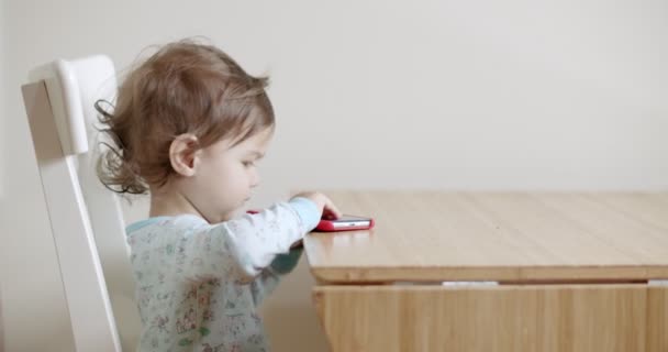 Ragazza Del Bambino Che Utilizza Telefono Cellulare Sul Tavolo Girato — Video Stock