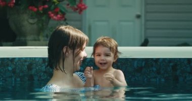 Anne ve küçük kızı yüzmenin keyfini çıkarıyorlar. 4K yaşam tarzı görüntüleri. RAW 'da bir sinema kamerasında çekildi..