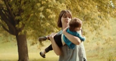 Anne ve bebek sonbahar sezonunun başlarında dışarıda oynuyorlar. 4K RAW 'da bir sinema kamerasında çekildi..