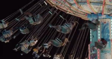 Geceleri karnaval salıncağının yavaş çekimleri. Görünürde yüz yok. 4K RAW 'da bir sinema kamerasında çekildi..