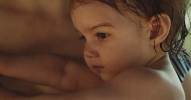 Anne yüzdükten sonra bebeğini kucağında tutuyor. 4K yaşam tarzı görüntüleri. RAW 'da bir sinema kamerasında çekildi..