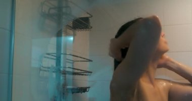 Duş alan güzel bir kadın. Biçimsel yansımalarla cam yoluyla çekilen.