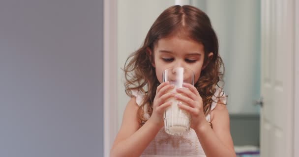かわいい幼児の女の子は牛乳を一杯飲んでいる 4K映像 — ストック動画