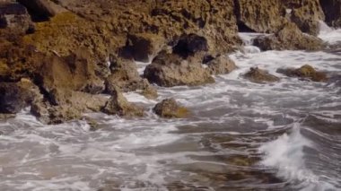 Dalgalar Porto Riko 'daki bir plajda kayalara çarpıyor. Sinematik 4K çekim yapıyor. Yavaş çekim.