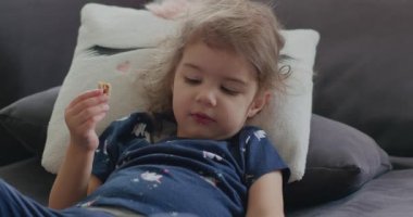 Evde abur cubur yiyen sevimli, komik küçük bir kızın portresi. 4K RAW 'da bir sinema kamerasında çekildi..