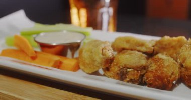 Sebze ve sosla servis edilen tavuk kanatları. 4K kaydırma atışı. Sinema kamerasıyla çekildi..