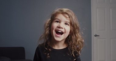 Küçük tatlı bir kızın komik suratlar yaptığı portre. 4K görüntü.