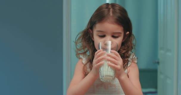 かわいい幼児の女の子は牛乳を一杯飲んでいる 4K映像 — ストック動画