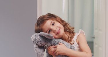 Küçük tatlı kız, pelüş oyuncağa sarılıyor. 4K görüntü.