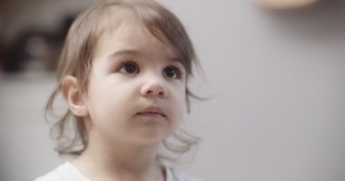 Normal bir günde evde sevimli, komik, küçük bir kızın portresi. 4K RAW 'da bir sinema kamerasında çekildi..