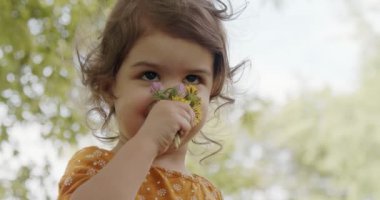 Küçük tatlı kız yazın parkın tadını çıkarıyor. Gerçek hayattaki görüntüler. 4K 'da çekilmiş..