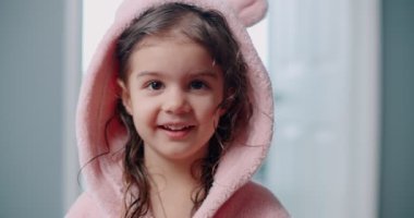 Banyodan sonra pembe bornozla poz veren tatlı bir kız. 4K görüntü.