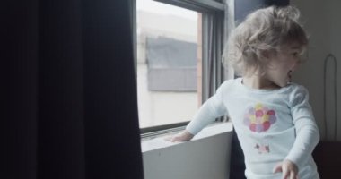 Bebek bebek COVID-19 tecridi sırasında pencereden dışarı bakıyor. 4K 'de vurulmuş. Gerçek hayat görüntüleri..
